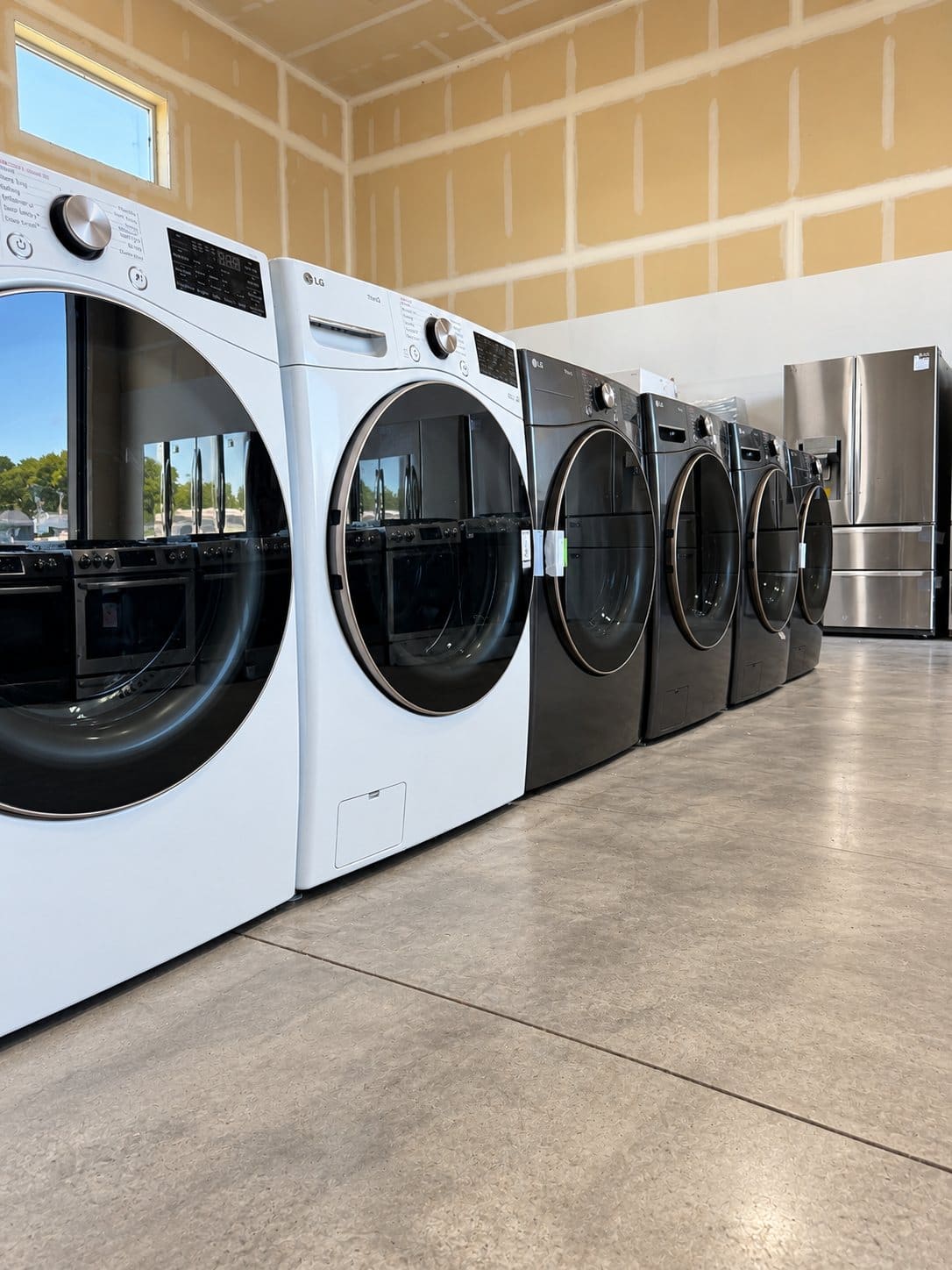 A long row of white and black front-load washers and dryers on the showroom floor