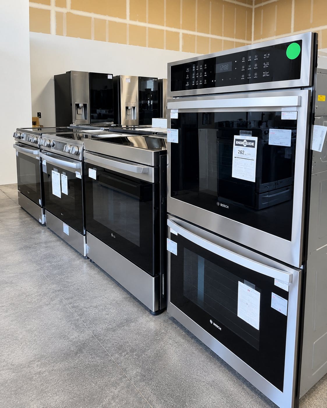 Ranges and Bosch wall ovens displayed beside refrigerators on the showroom floor